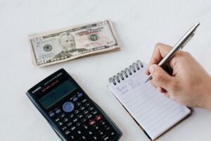 Close-up of budgeting items including calculator, cash, and notebook for financial planning.